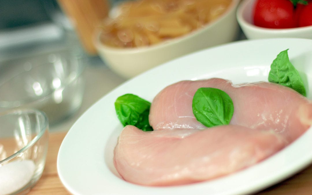 How To Buy Chicken. Chicken breast fillets with herb leaves on a plate.