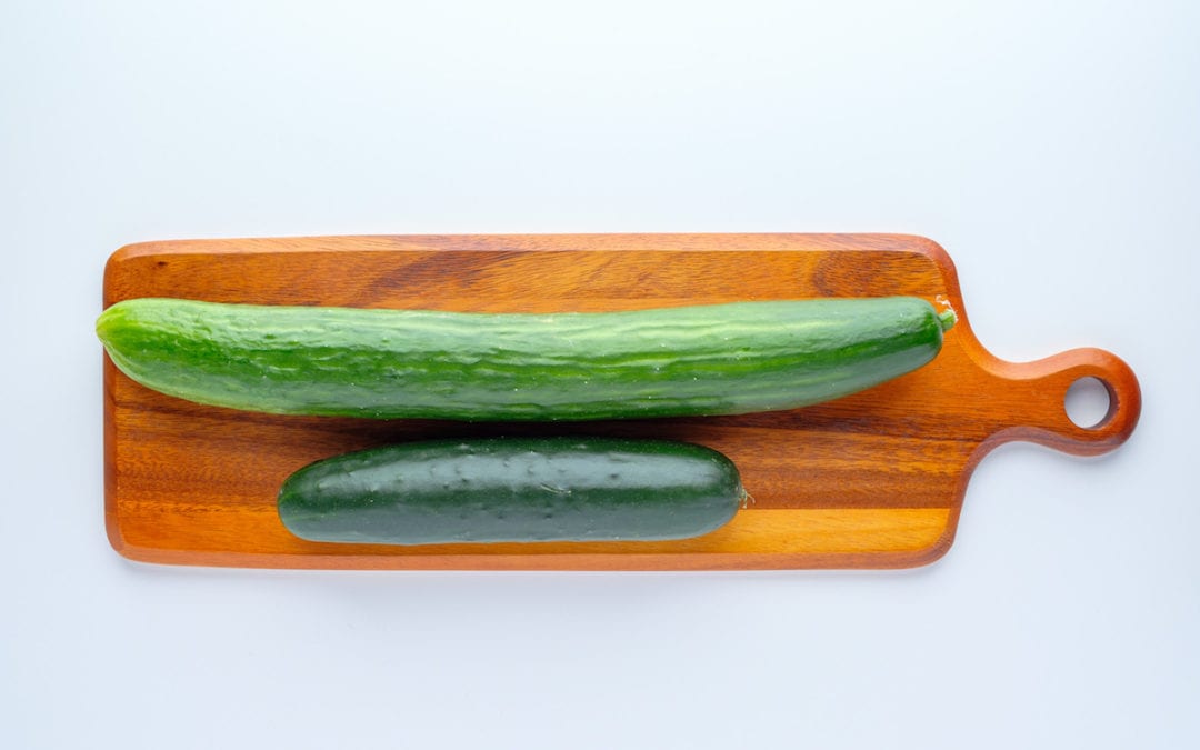 Difference Between Slicing and English Cucumbers. | English and slicing cucumbers on top of a wooden chopping board.