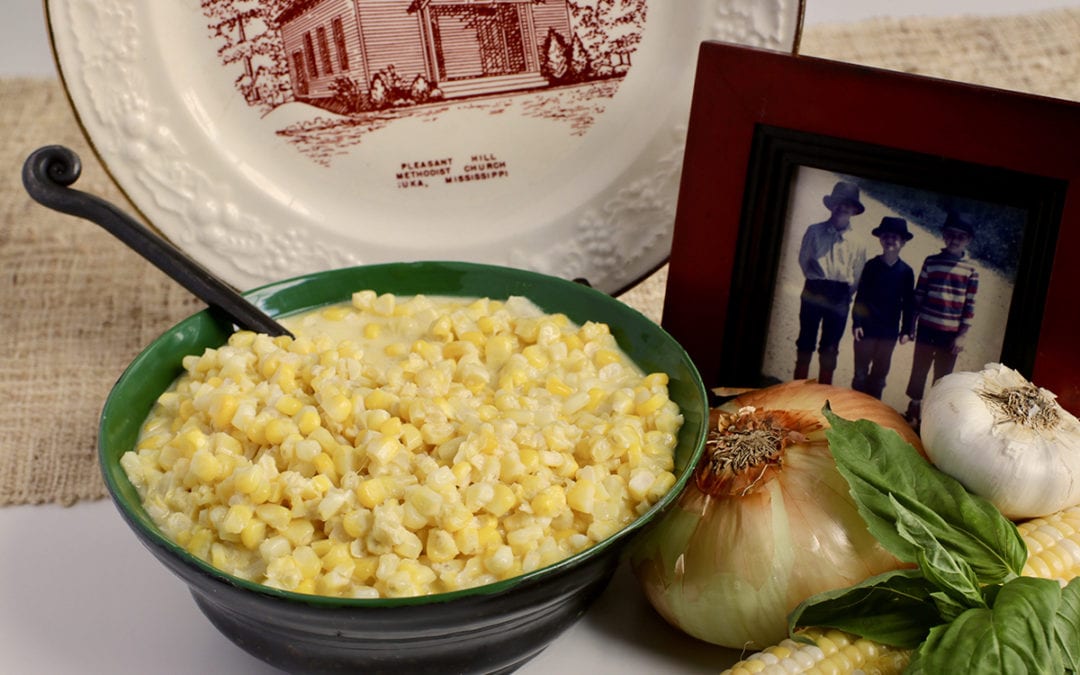 Life At The Table | Creamed Corn Recipe | Creamed corn in a bowl surrounded by a plate with a picture of an old church and a photo of three kids in fishing gear.