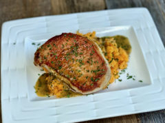 Life At The Table | Pan-Seared pork chops with a white wine, orange, thyme sauce served over mashed sweet potatoes on a white plate.