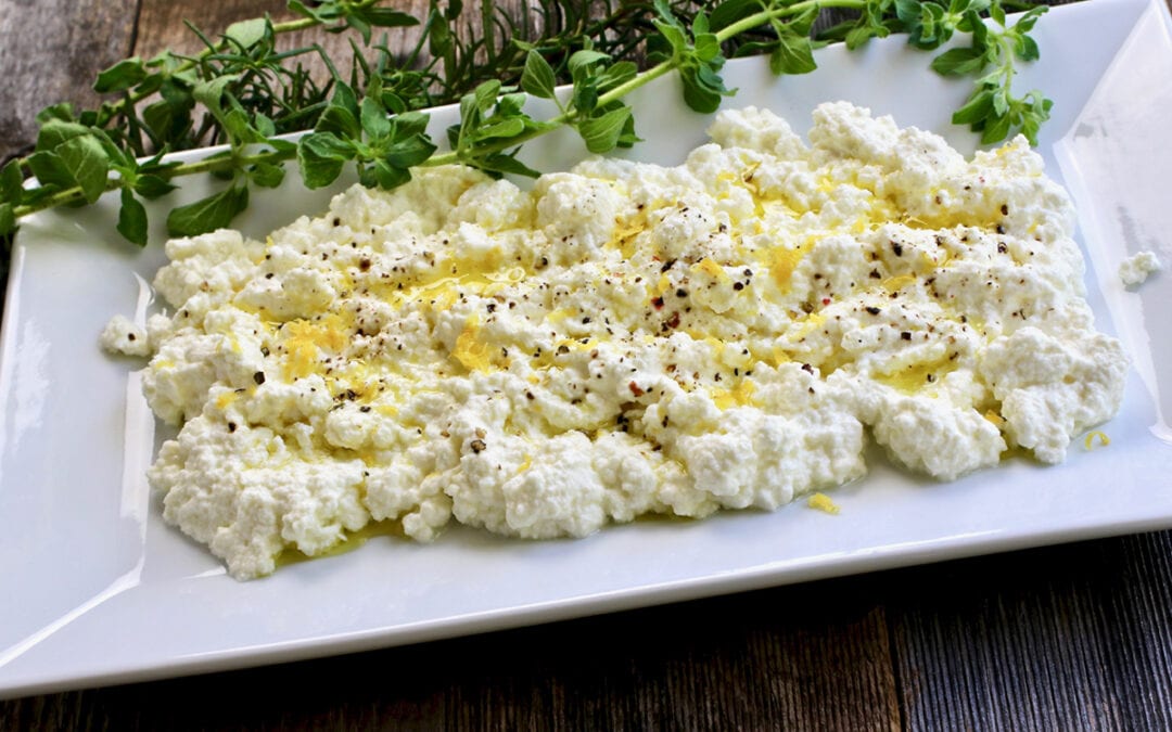 Homemade Ricotta Cheese | Prepared homemade ricotta on a square white plate with herbs on the side.