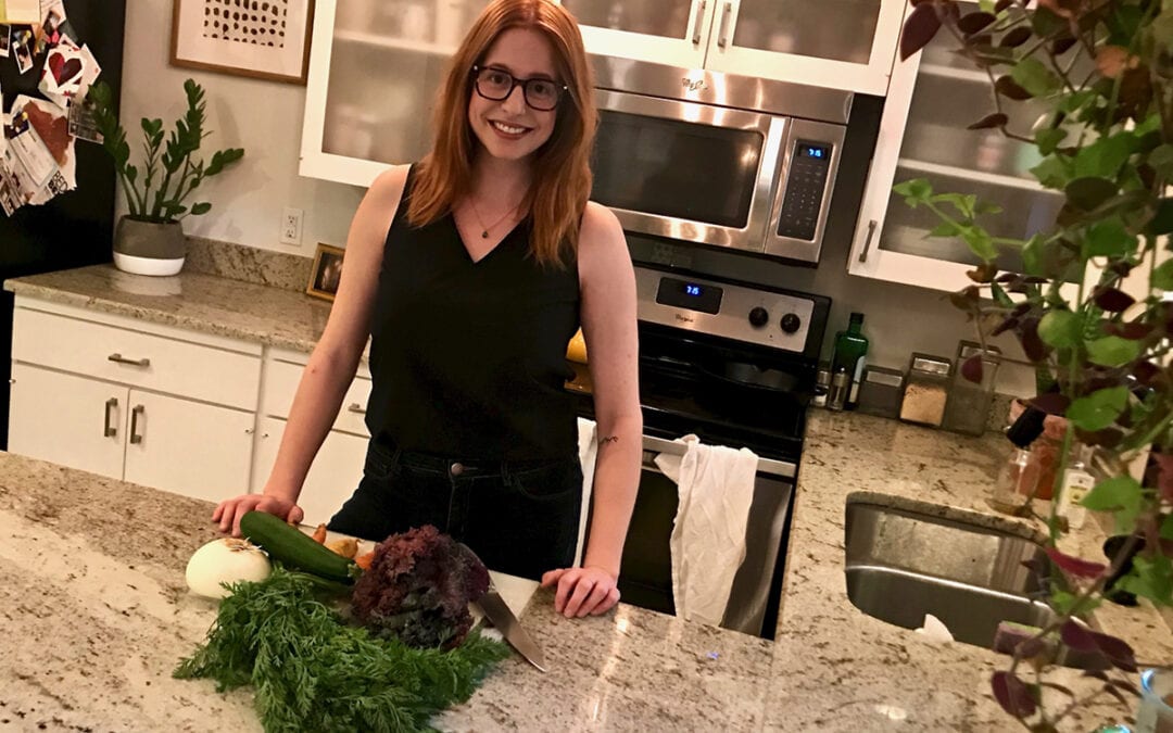 Life at the Table | Single lifestyle cooking Hannah Clayton in front of her kitchen counter with salad greens
