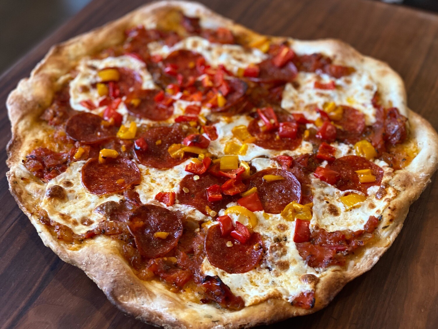 Life At The Table Virtual Culinary Team Building Events. A flatbread pepperoni pizza sitting on a wooden cutting board.