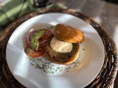 Life At The Table falafel burger | Falafel burger on a white plate topped with spicy yogurt sauce