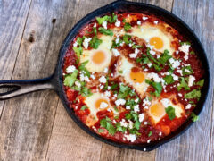 Shakshuka in a cast iron pan on a wooden table.