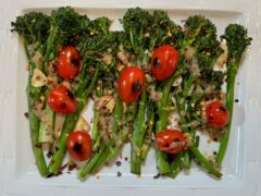 Life At The Table | Roasted Broccolini. Roasted broccolini with garlic and blistered tomatoes on a white plate garnished with red pepper flakes.