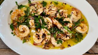 Life At The Table Shrimp al Ajillo. Shrimp al ajillo on a white plate garnished parsley.