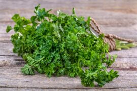 Life At The Table Tabbouleh. A bunch of curly parsley tied with a string lying on a wooden table.