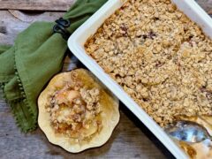 Life At The Table Fruit Crisp. A fresh apple fruit crisp in a white casserole dish with a portion of it scooped out onto a small plate with a green napkin beside it.