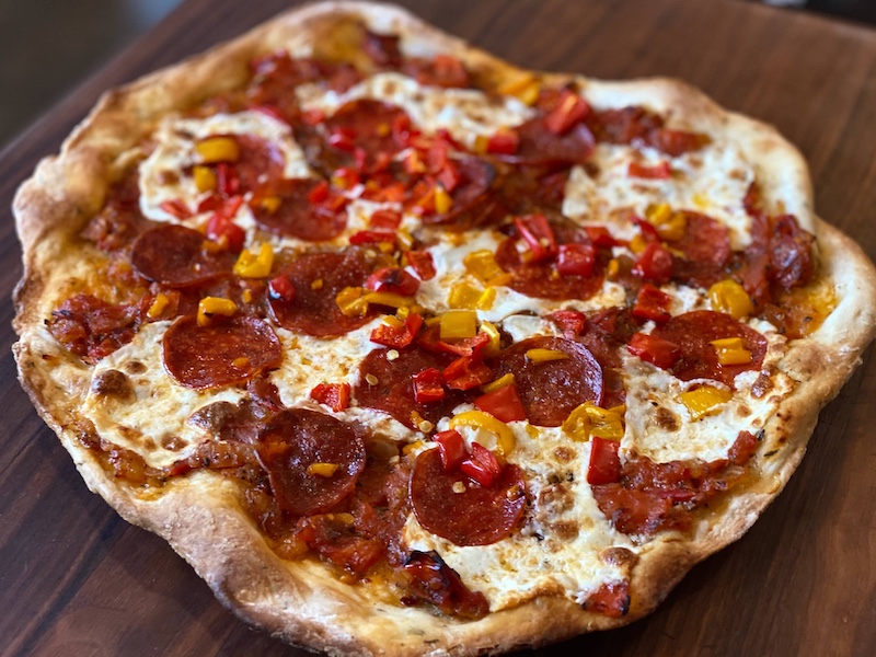 Life At The Table Flatbread Pizza Virtual Cooking Class. A flatbread pepperoni pizza on a wooden surface.